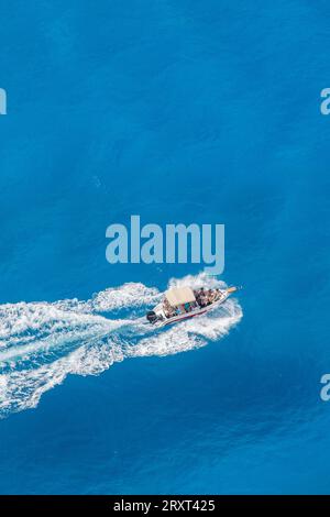 Kleines Vergnügungsboot oder Schnellboot, das auf der griechischen Insel zante oder zakynthos über ein klares blauazurblaues mittelmeer segelt. Stockfoto