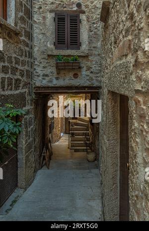 Gassen und Treppen zwischen Steinhäusern und bunten Blumenkästen im mittelalterlichen Dorf Castel Trosino. Ascoli Piceno, Region Marken, Stockfoto