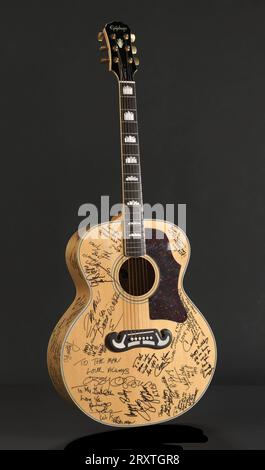 Eine Epiphone-Gitarre und ein TKL Products Corp.-Gehäuse im Besitz von James Brown. Die sechssaitige Akustikgitarre ist Epiphone Modell EJ-200NA und hat einen Ahornkörper sowie eine Fichtenspitze und -Hals. Die Gitarre verfügt außerdem über goldfarbene Metallbeschläge und einen Ahornhals mit einer Kronen-Intarsie auf einem Palisander-Griffbrett. Die Seriennummer der Gitarre lautet Y207183. Die Gitarre ist von mehreren berühmten Personen in schwarzer Permanentmarkierung auf der Vorder-, Seiten- und Rückseite des Körpers beschriftet und signiert. Alle Botschaften sind an James Brown gerichtet und loben und danken. Zwei der Personen, die die Gitarre unterschrieben haben, sind Casey Ka Stockfoto