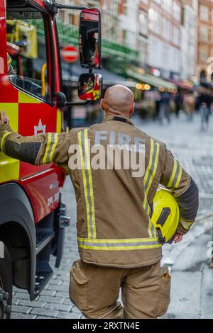 Ein kahlköpfiger Feuerwehrmann am Tatort eines Vorfalls in London. Stockfoto