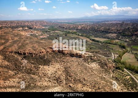 Drohnen-Luftaufnahme einer Straße, die eine wüstenartige Landschaft in der Nähe des Francisco Abellan Dam und Reservoir, Granada, Andalusien, Spanien, Europa überquert Stockfoto