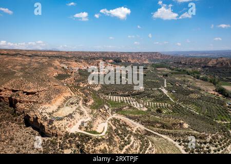 Drohnen-Luftaufnahme einer Straße, die eine wüstenartige Landschaft am Francisco Abellan Dam, Granada, Andalusien, Spanien, Europa überquert Stockfoto