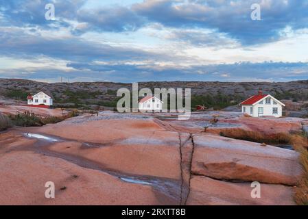 Drei isolierte Häuser auf der roten Granitinsel in der Abenddämmerung, Bohuslan, Vastra Gotaland, Westschweden, Schweden, Skandinavien, Europa Stockfoto