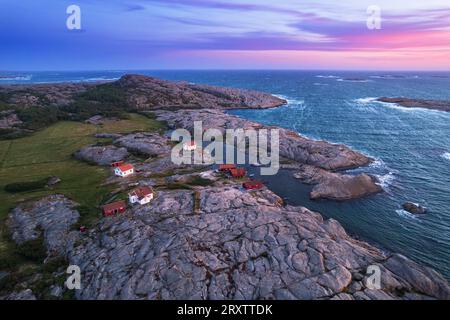 Aus der Vogelperspektive auf die malerische Landschaft aus Granitfelsen mit abgelegenen Häusern und roten Hütten entlang der Küste, Ramsvik Insel, Bohuslan Stockfoto