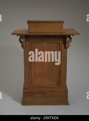 Podium in der Wayman Chapel A.M.E. Church in Lyles Station, Indiana. Das Podium besteht aus Holz und hat Metallnägel, Scharniere und Schrankbeschläge. Auf der Oberseite des Podiums befindet sich ein Buchständer aus Holz, der an einem großen flachen Stück Holz befestigt ist. Auf beiden Seiten sind an der Oberseite gekrümmte Holzhalterungen angebracht. An der Rückseite des Podiums ist eine Kabinetttür angebracht. Die Tür hat eine Metallverriegelung auf der linken Seite und zwei Scharniere auf der rechten Seite. Stockfoto