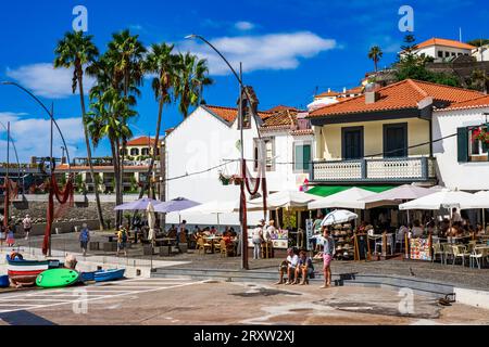 Malerischer Blick auf das kleine Fischerdorf Câmara de Lobos in Madeira, Portugal, wo Touristen das Hafenleben an der Uferpromenade genießen Stockfoto