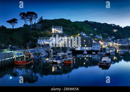 Cottages und Lichter und Fischerboote spiegeln sich im Hafen des kornischen Fischerdorfes Polperro wider, während die Abenddämmerung in die Nacht übergeht. Cornwall, England, Großbritannien Stockfoto