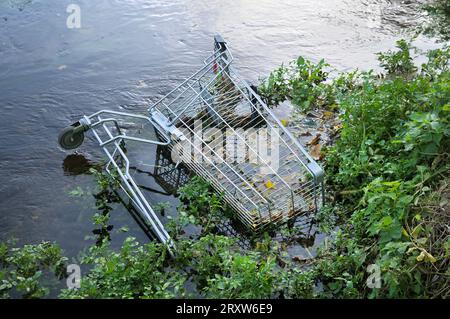 Verlassener Einkaufswagen, der in einem britischen Fluss untergetaucht ist. Asoziales Verhalten, umweltschädlich, Augenschmerzen, Flussverschmutzung, Gefahren, Flüsse, Wasser Stockfoto