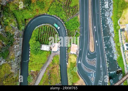 Wunderschöner Blick aus der Vogelperspektive auf eine Bergstraße, die entlang eines Berges führt, mit einem Lastwagen, der die Serpentinen hinunterfährt, Madeira, Portugal Stockfoto