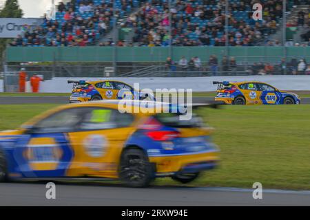 Das Trio des Napa Racing UK Ford Focus fährt um die Luffield-Ecke in Silverstone vor den Zuschauern auf der großen Tribüne der BTCC 2023 Stockfoto