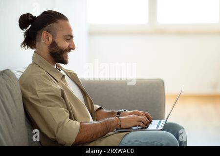 Seitenansicht des gutaussehenden Mannes, der auf der Laptop-Tastatur schreibt Stockfoto