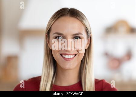 Glückliche schöne Millennials Frau posiert zu Hause und lächelt vor der Kamera Stockfoto