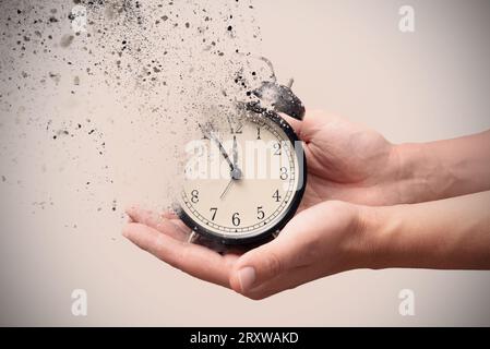 Das Konzept des Vergehens zerfällt die Uhr in Stücke. Alter Wecker in den Händen. Stockfoto