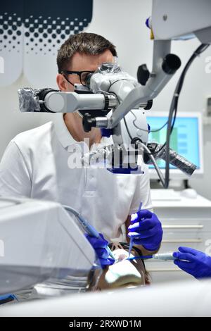 Der Zahnarzt untersucht die Zähne des Patienten mit einem zahnärztlichen Mikroskop Stockfoto