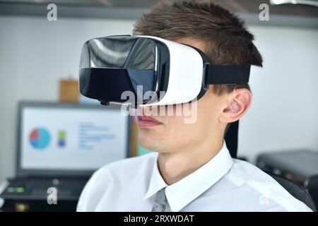 Junger Geschäftsmann mit VR-Brille, der an einem virtuellen Geschäftsbericht arbeitet. Nahaufnahme Stockfoto