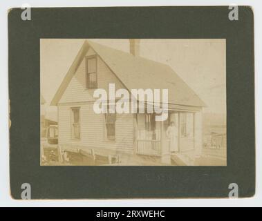 Foto einer Frau, die auf der Veranda eines Hauses zu Beginn des 20. Jahrhunderts steht Stockfoto