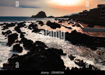 Fantastischer Blick auf die Menschen in den natürlichen Lavapools in Porto Moniz, Madeira, Portugal, während das Meer außerhalb des natürlichen Wellenbrechers tobt Stockfoto