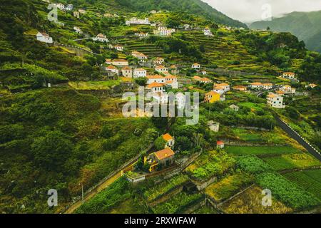 Malerische und wunderschöne Aussicht aus der Luft auf das kleine Bergdorf Ribeira da Janela auf Madeira, Portugal, das sich entlang eines Berges erstreckt Stockfoto