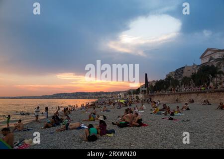 Badende und Sonnenanbeter bleiben am Strand von Nizza in Frankreich nach Sonnenuntergang und in den heißen Abend und die warme Nacht. (135) Stockfoto