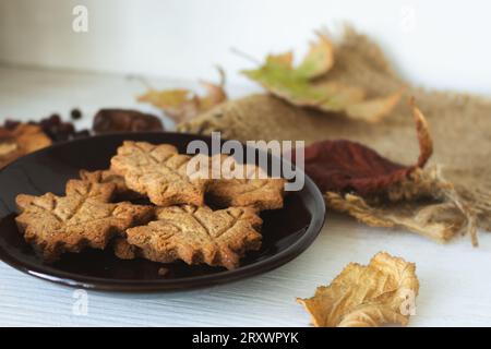 Zimtkekse und Herbstblätter auf Holzregal. Lebkuchen-Kekse in Blattform. Festliche Herbstkekse. Handgemachte Bäckerei. Stockfoto