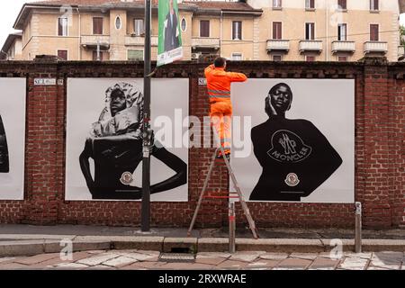 Mailand, Italien - 21. April 2023: Ein Arbeiter stellt Plakate auf, die die Moncler-Kollektion von 2023 an den Wänden zeigen Stockfoto