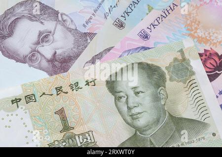 Nahaufnahme einer chinesischen Yuan-Banknote, die auf ukrainischen Hrivnya-Banknoten liegt Stockfoto