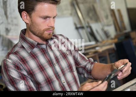 Mann, der in der Werkstatt an der Metallstange gemessen wird Stockfoto