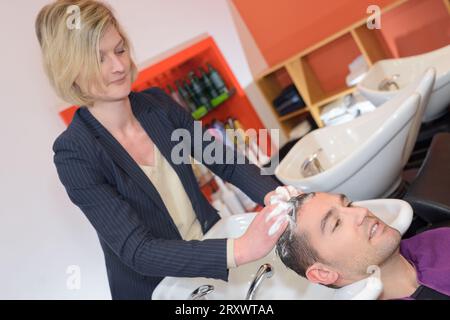 Weibliche Friseurin wäscht Männerhaare im Friseursalon Stockfoto