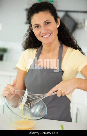 Frau, die eine Schüssel hält und Eier schlägt Stockfoto