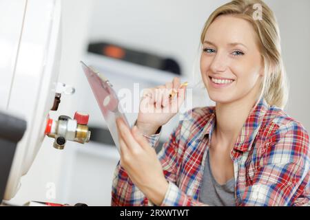 Weibliche Klempner Arbeiten an zentralen Heizkessel Stockfoto