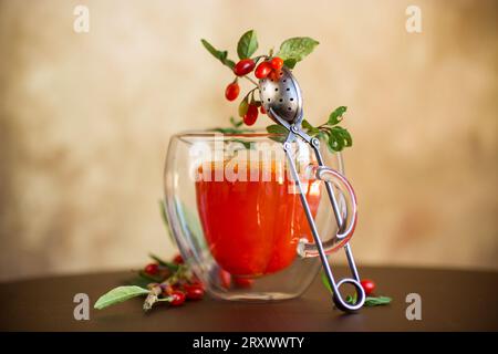 Zubereitetes Heißgetränk aus Reifen Goji-Beeren in einer Glasschale auf einem Holztisch. Stockfoto