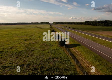 Drohnengesichtspunkt der Trennung zwischen Autobahn und Landwirtschaftsfeld am Sommertag Stockfoto