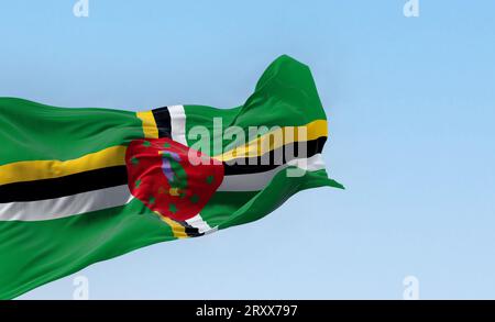 Dominica Nationalflagge, die an klaren Tagen winkt. Grünes Feld, ein Kreuz aus Gelb, Schwarz und Weiß, eine rote Scheibe mit einem lila Sisserou-Papagei und zehn gree Stockfoto