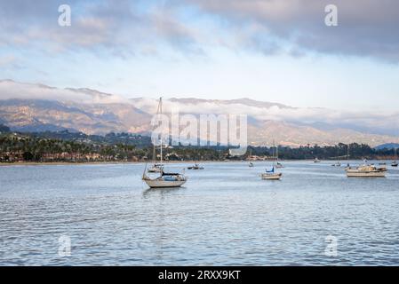 Yachten ankerten am Strand von Santa Barbara bei Sonnenuntergang im Herbst. Im Hintergrund sind gewaltige Berge zu sehen. Stockfoto