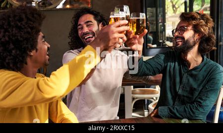 Eine kleine Gruppe von Freunden verschiedener Rassen, die gemeinsam in einer Bar Bier trinken. Stockfoto