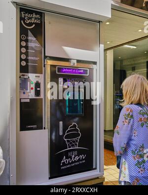 Eine Frau kauft eine Eiskegel an einem Automaten auf der Straße in Cochem, Deutschland. Stockfoto