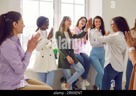 Glückliche weibliche Kollegen geben High Five beim Meeting, um Erfolg oder Geschäftserfolg zu feiern. Stockfoto