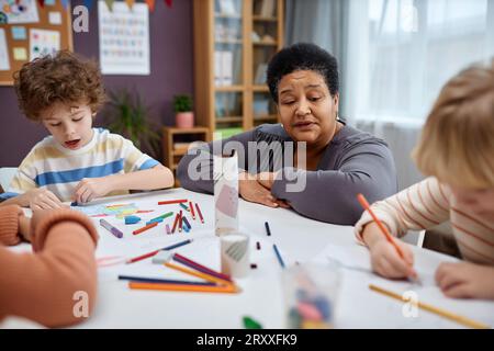 Porträt einer Reifen Schwarzen Frau als Lehrerin, die mit Kindern in der Kunst- und Handwerksklasse im Vorschulalter arbeitet Stockfoto