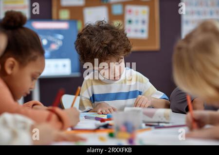 Porträt von süßen Jungen Malbilder am Tisch mit einer Gruppe von Kindern in Kunst- und Bastelunterricht im Vorschulalter, Kopierraum Stockfoto