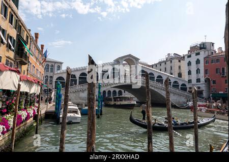 Ein vertrauter Anblick eines Gondoliers, der seine Gondel auf dem Canal Grande (Canal Grande) in der Nähe eines der prominenten Wahrzeichen Venedigs, der Rialto-Brücke, rudert Stockfoto