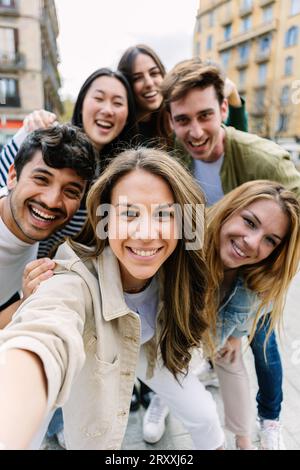 Vertikale Aufnahme von jungen Millennials, die Selfie mit dem Telefon auf der Straße machen Stockfoto