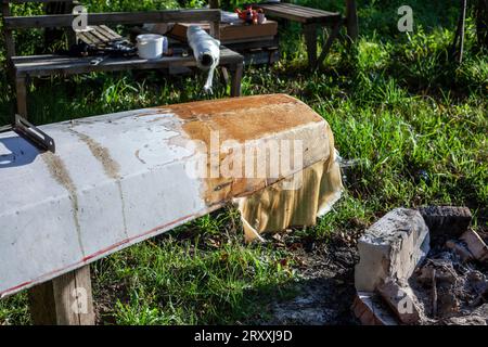 Bootsreparatur. Tragen Sie Harz auf das Boot auf. Klebriges Material. Reparatur eines Schwimmschiffes. Stockfoto