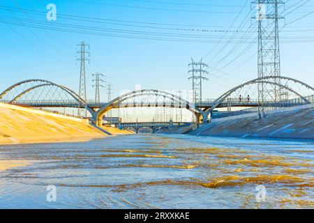 Blick auf zwei Brücken über den reißenden Los Angeles River an einem sonnigen Wintertag. Stockfoto