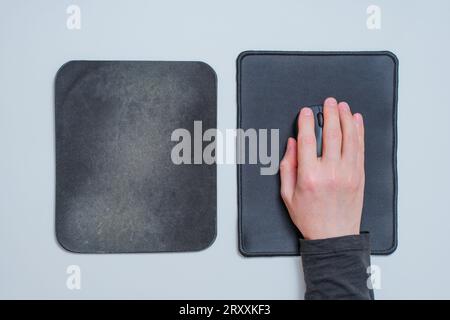 Schnittansicht einer männlichen Hand mit einer Computermaus auf einem brandneuen Mauspad, das von der alten und schäbigen Maus gesetzt wurde. Stockfoto