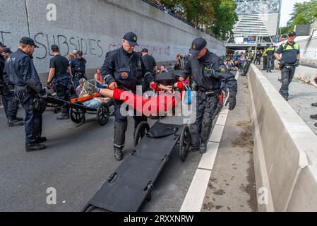 27. September 2023, den Haag, Südholland, Niederlande: Die niederländische Polizei nutzt Radtrage, um verhaftete Klimaaktivisten zu bewegen. Am 27. September 2023 führen die Aktivisten der Extinction Rebellion auf der Autobahn A12 in den Haag ein „die-in“ durch. Die Aktivisten protestieren gegen die Subventionen und Steuervergünstigungen der niederländischen Regierung für die fossile Brennstoffindustrie. (Bild: © James Petermeier/ZUMA Press Wire) NUR REDAKTIONELLE VERWENDUNG! Nicht für kommerzielle ZWECKE! Stockfoto