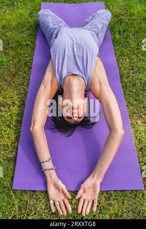 HIGG-Winkelansicht einer Frau, die auf einem Yoga-Block liegt, um die Körperhaltung zu verbessern Stockfoto