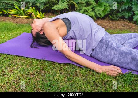 Die Frau liegt auf einem Yogablock, um die Körperhaltung zu verbessern Stockfoto