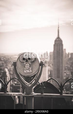 Altmodische münzbetriebene Ferngläser mit Blick auf das Empire State Building und das umgebende Viertel in Midtown Manhattan vom Top of the Rock in Stockfoto