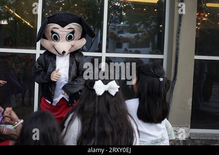 Partyclown oder Charakter, der mit den Kindern spielt. Geburtstagsfeier für Kinder im Freien. Kinder spielen mit Clown. Kinder spielen mit der Person, die micky Maus trägt Stockfoto