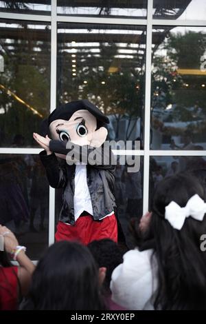 Partyclown oder Charakter, der mit den Kindern spielt. Geburtstagsfeier für Kinder im Freien. Kinder spielen mit Clown. Kinder spielen mit der Person, die micky Maus trägt Stockfoto